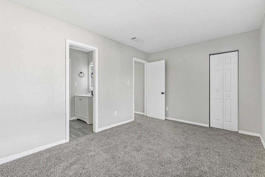 A room with a carpeted floor and two doors.