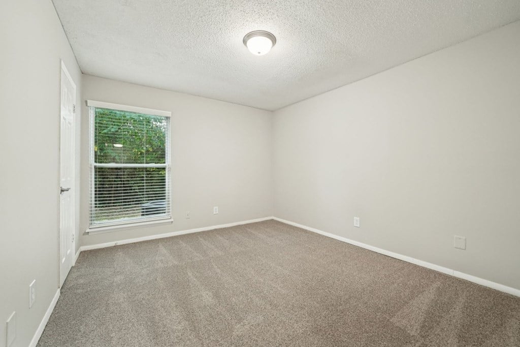 A room with a carpeted floor and a window with blinds.at Hills at Hoover Apartments, Hoover, 35216