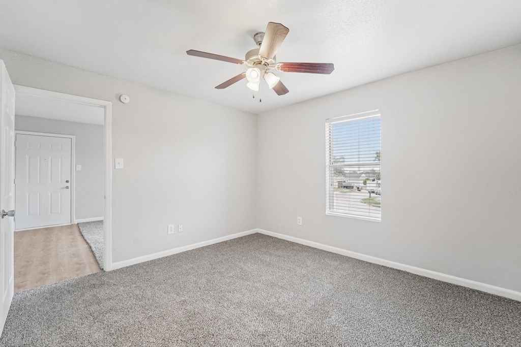 A room with a ceiling fan and a window with blinds.
