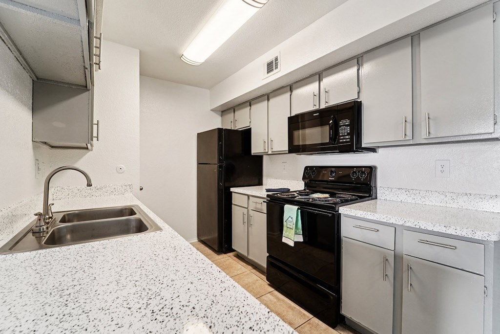 A kitchen with black appliances and white cabinets.
