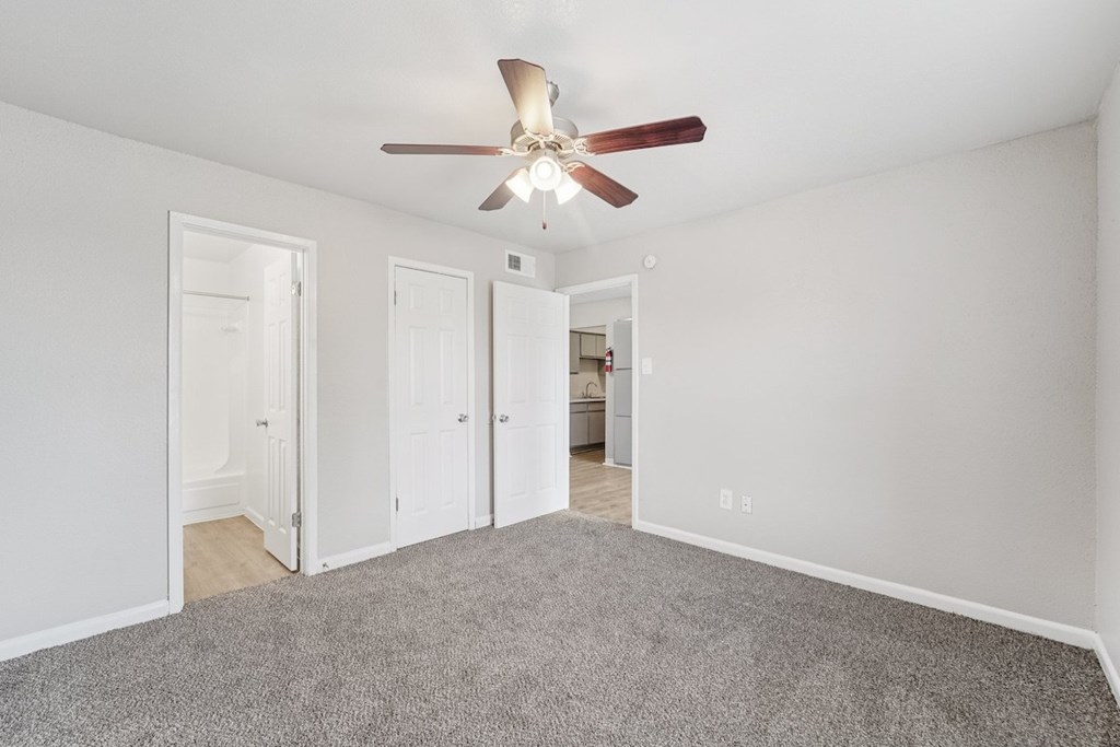 A room with a ceiling fan and carpeted floor.