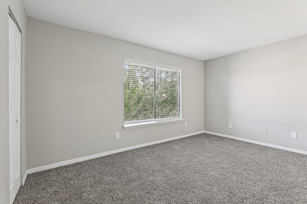 A room with a window and carpeted floor.
