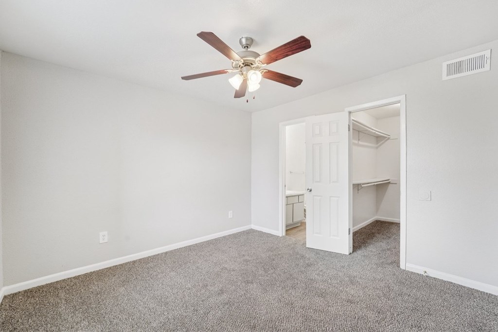 A room with a ceiling fan and carpeted floor.