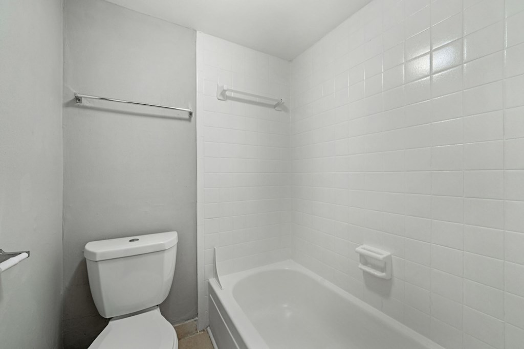 A white bathroom with a toilet, tub, and towel rack.at Hills at Hoover Apartments, Hoover, AL 35216