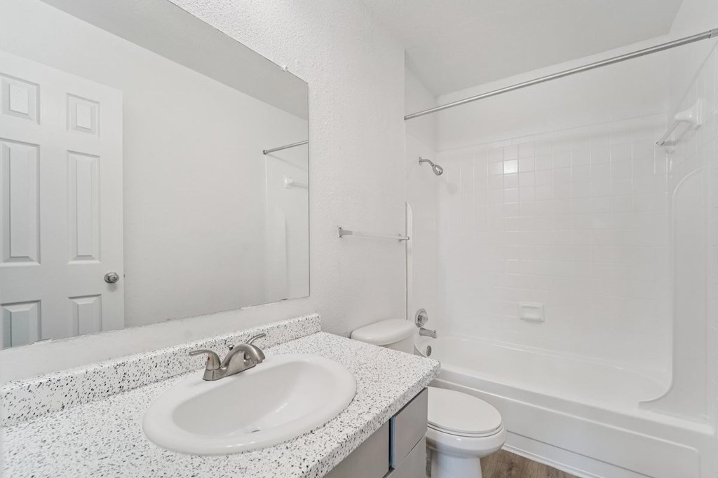 A white bathroom with a sink, toilet, and bathtub.