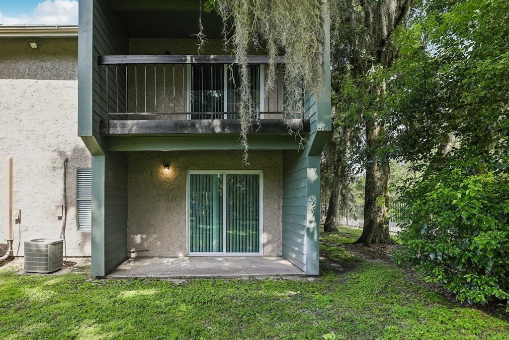 A balcony with a green door is surrounded by greenery.