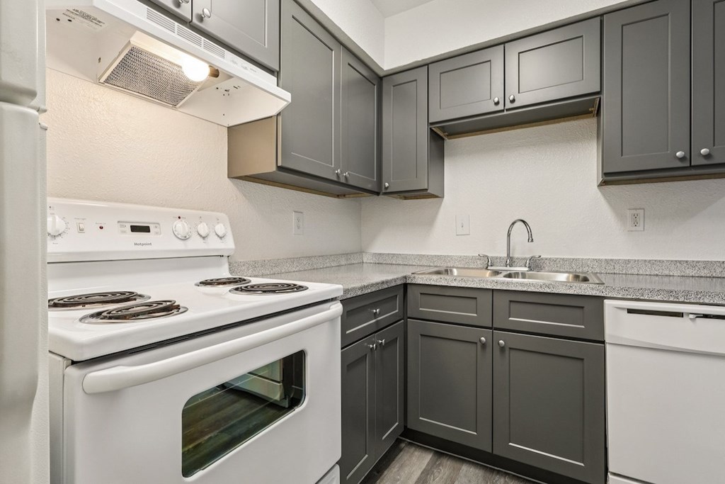 A kitchen with a white stove and black cabinets.