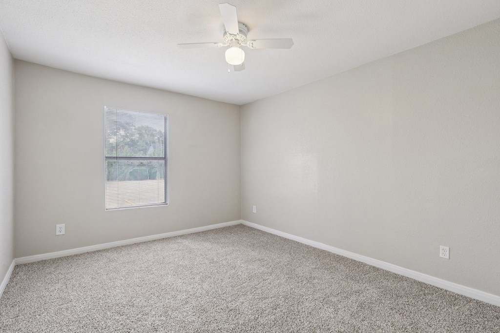 A room with a ceiling fan and carpeted floor.