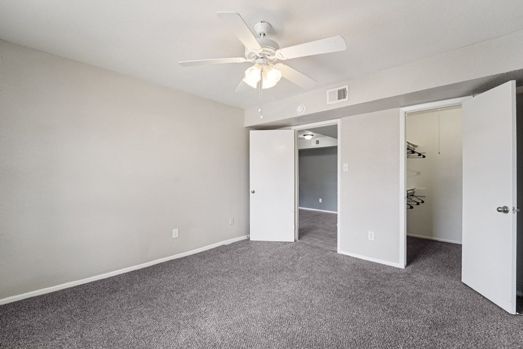 A room with a ceiling fan and carpeted floor.