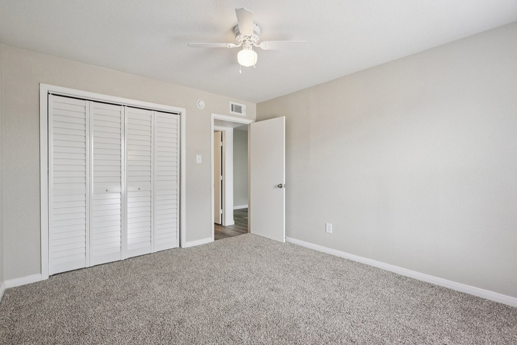 A room with a ceiling fan and carpeted floor.