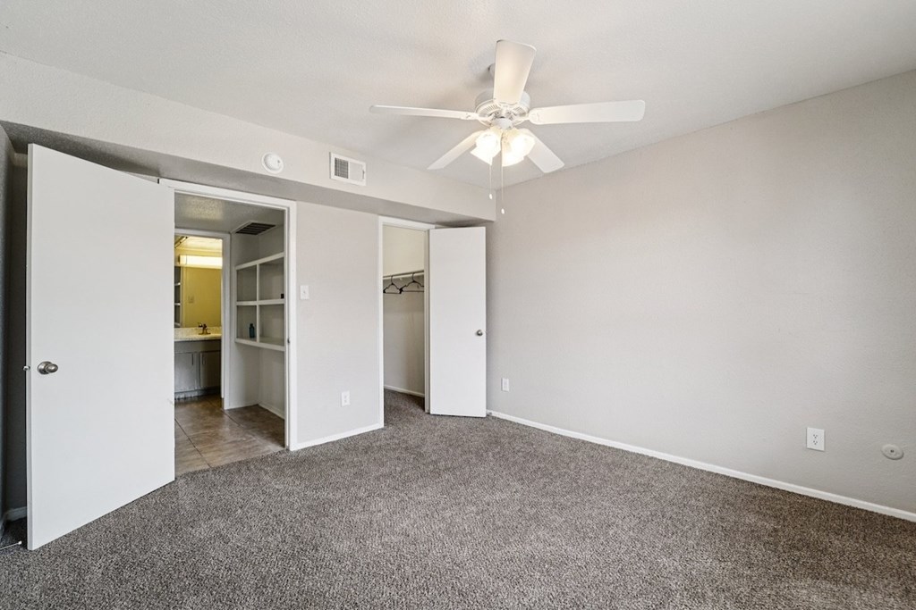 A room with a ceiling fan and carpeted floor.