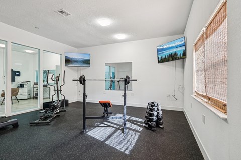 A gym room with a variety of equipment including a treadmill, exercise bike, and weight stacks.