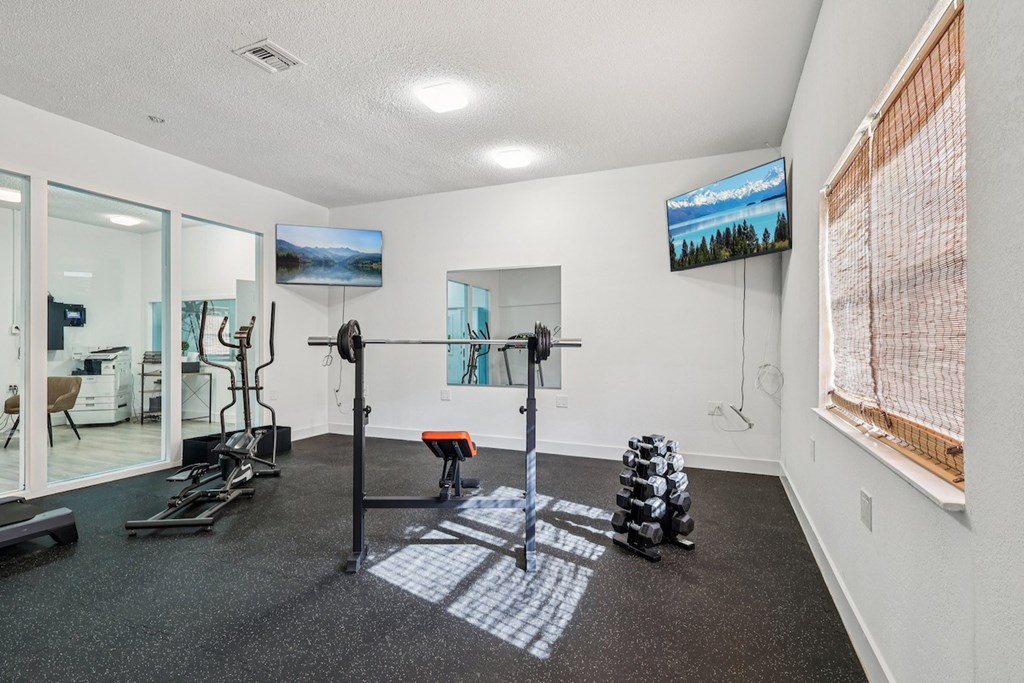 A gym room with a variety of equipment including a treadmill, exercise bike, and weight stacks.