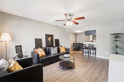 A living room with a black couch and a ceiling fan.