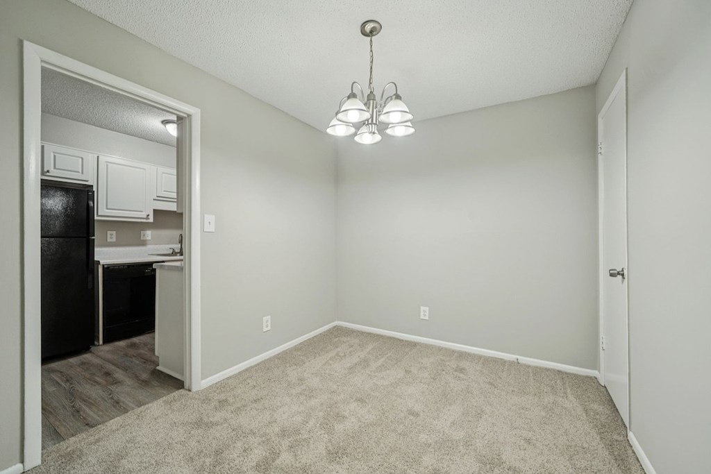 A small, empty room with a carpeted floor and a chandelier hanging from the ceilingat Hills at Hoover Apartments, Hoover, AL.
