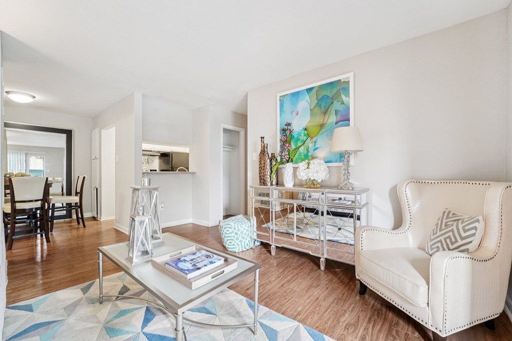 A living room with a white couch, a glass coffee table, and a painting on the wall.