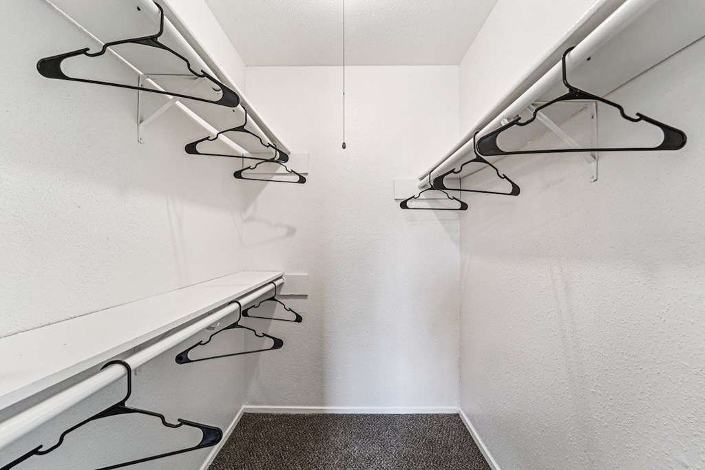 A hallway with white walls and black hangers on the wall.