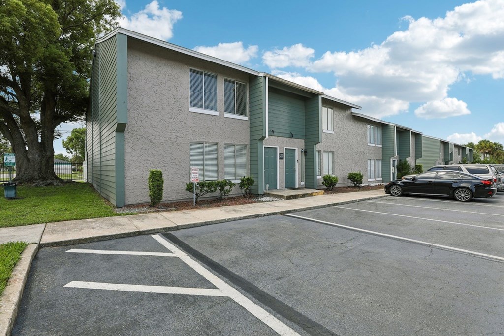 A parking lot in front of a building with a car parked.