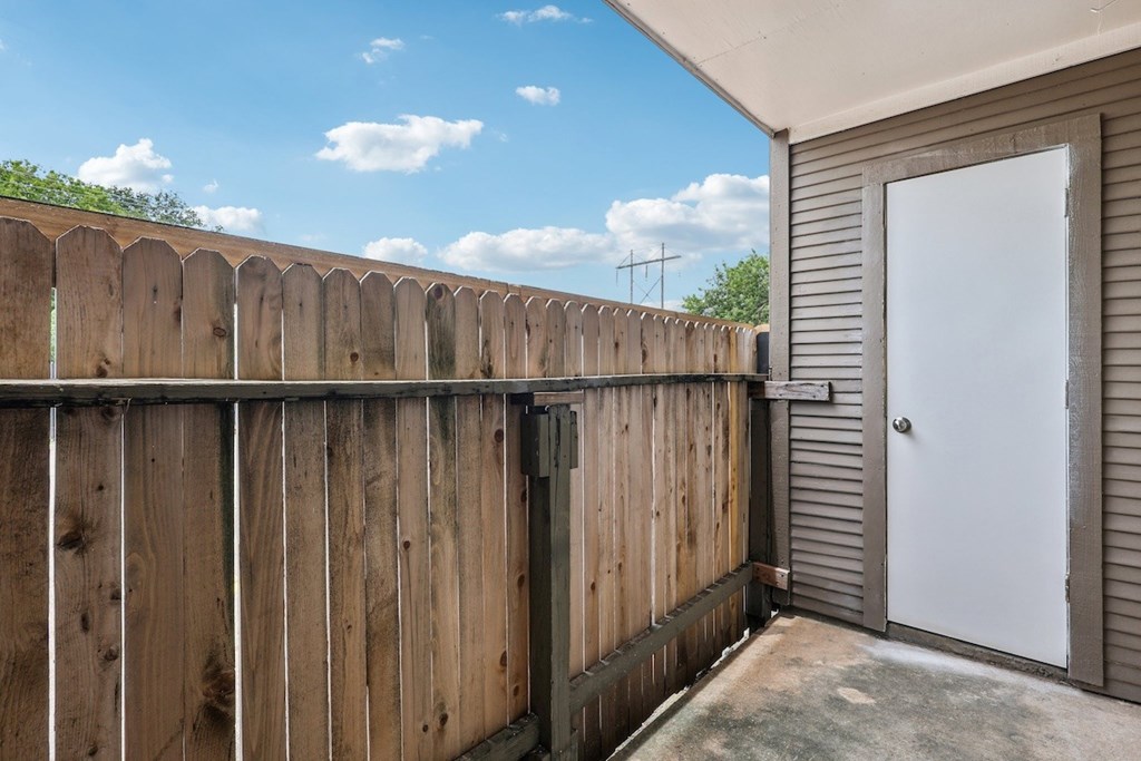 A wooden fence with a white door and a grey wall.