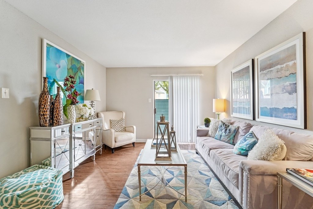 A living room with a grey couch and a painting on the wall.