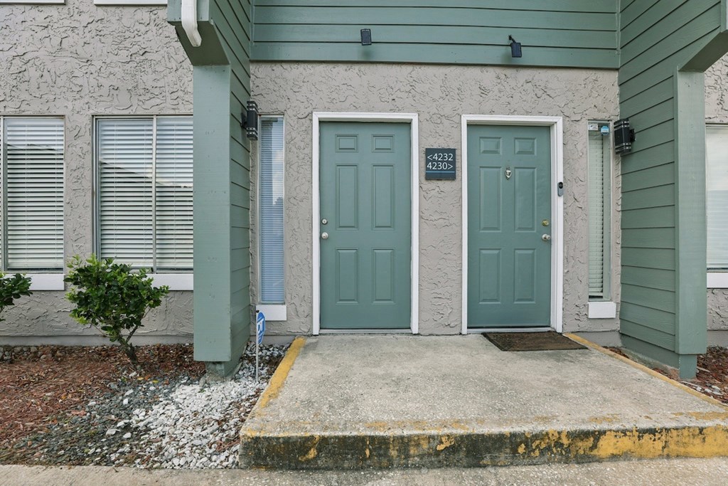 A green house with a white door and windows.