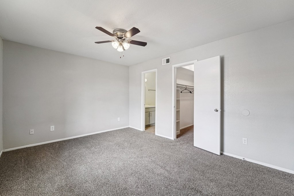 A room with a ceiling fan and carpeted floor.