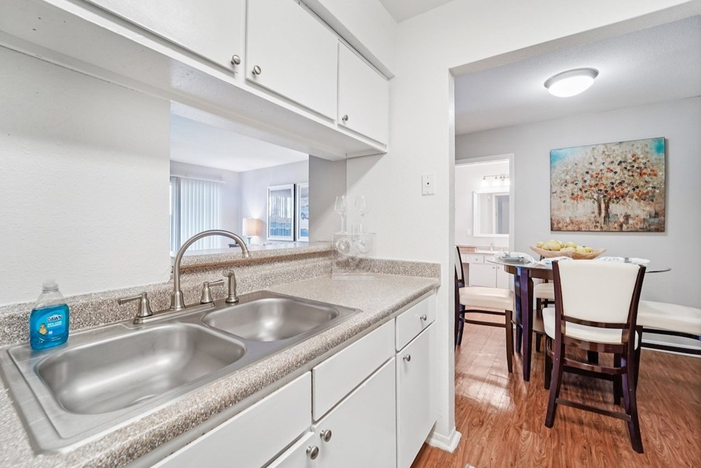 A kitchen with a sink, a dining table and chairs.