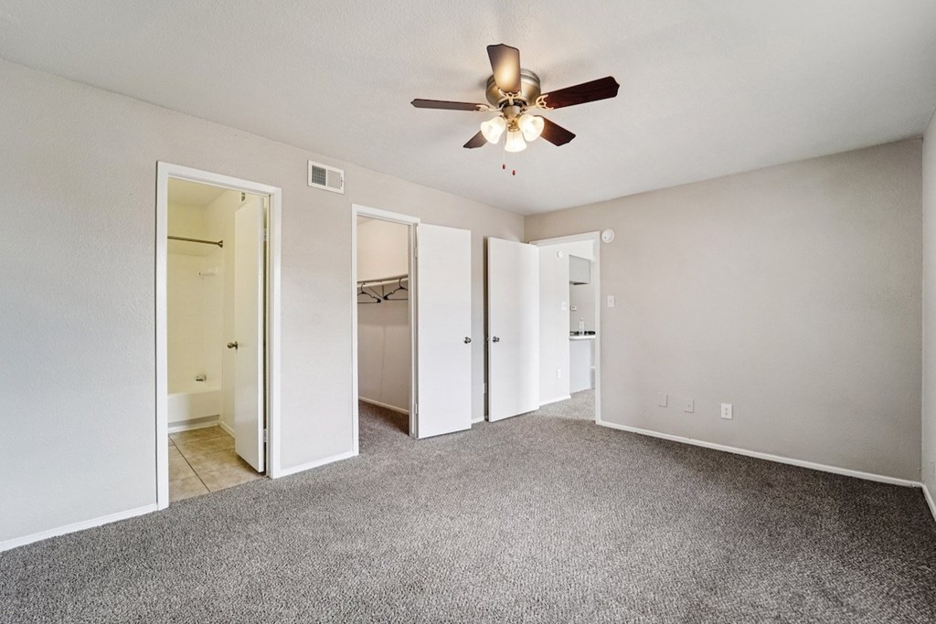 A room with a ceiling fan and carpeted floor.