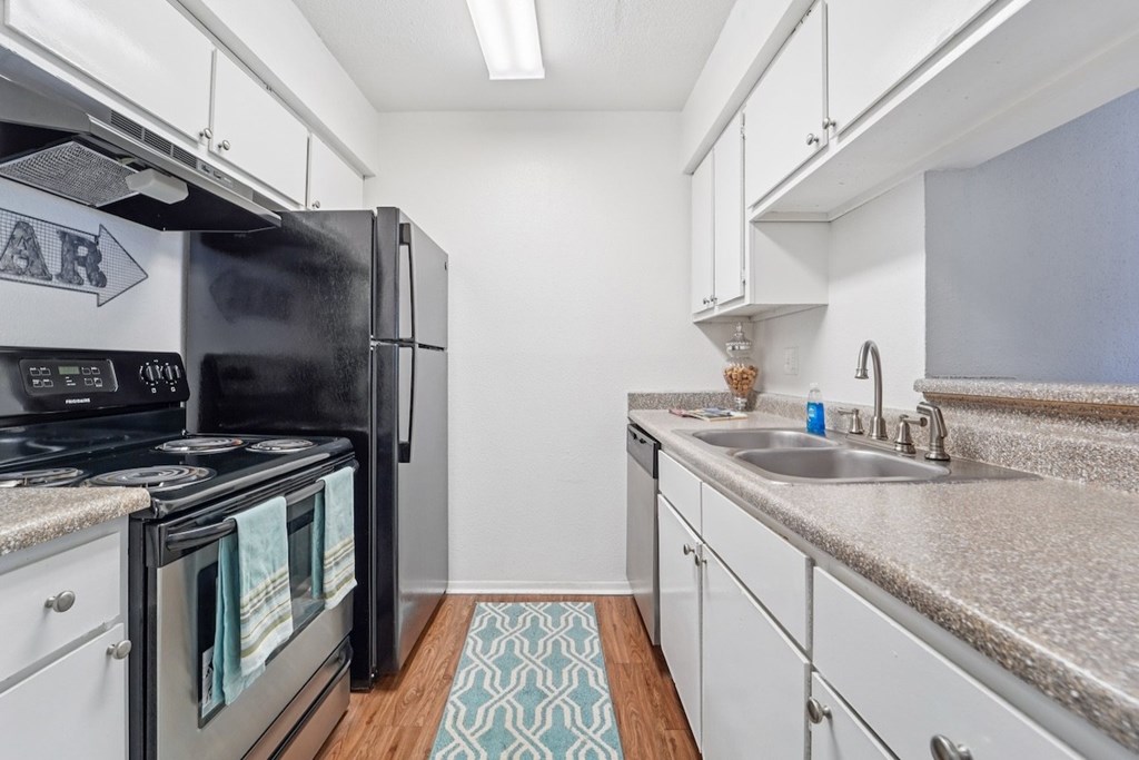 A kitchen with a black refrigerator and white cabinets.