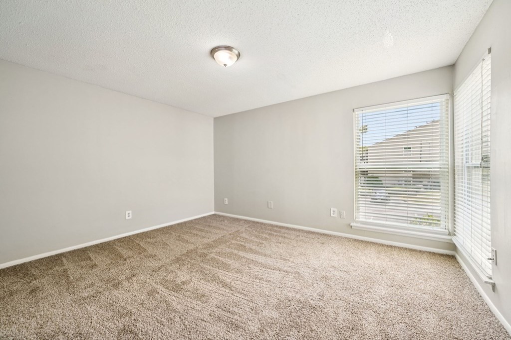 A room with a carpeted floor and a window with blinds.at Hills at Hoover Apartments, Alabama