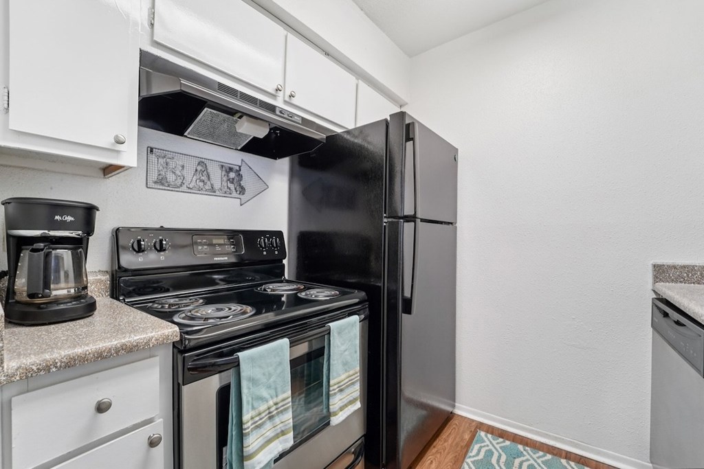 A black refrigerator is in a kitchen with a white counter top.