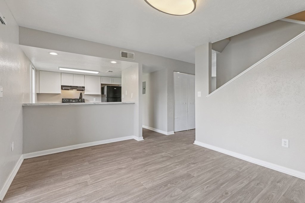 A spacious room with a kitchenette and a staircase.