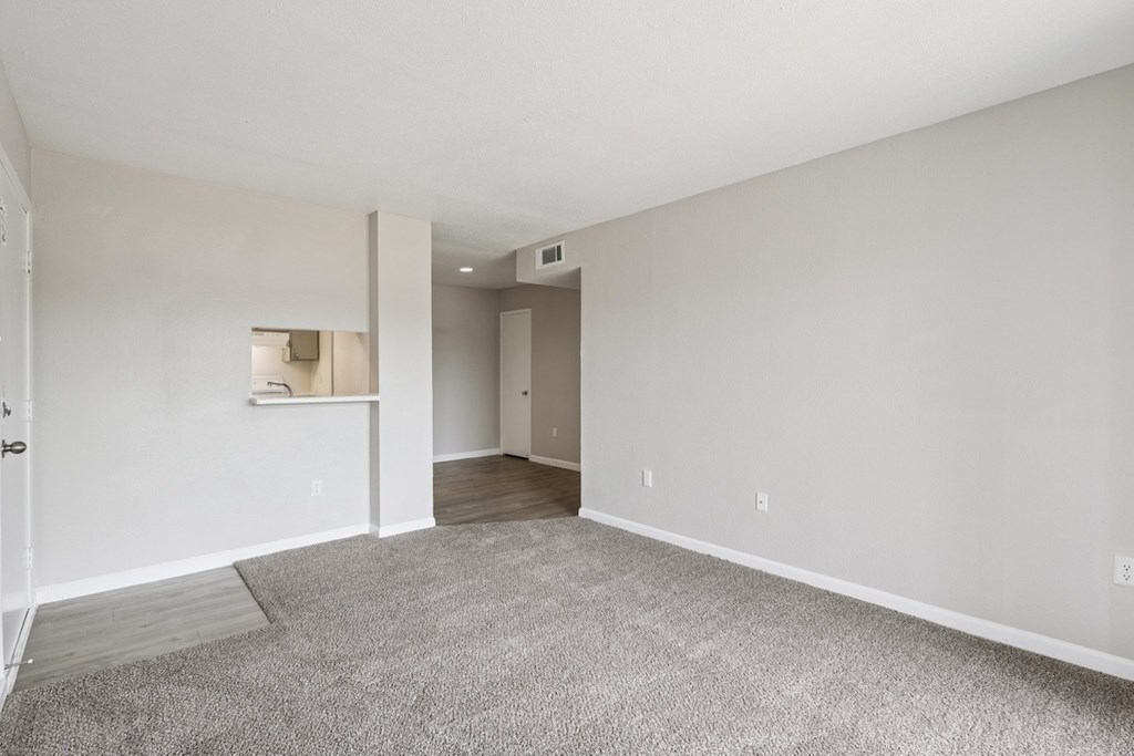 A spacious room with a carpeted floor and white walls.