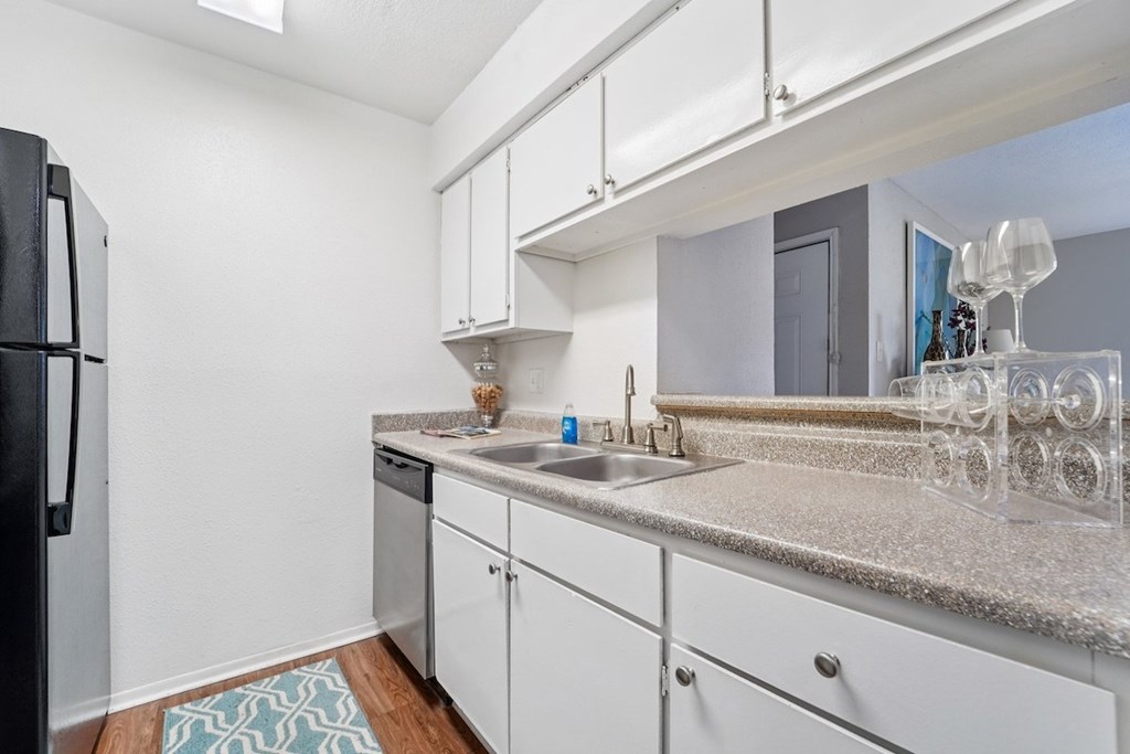 A kitchen with a black fridge and white cabinets.