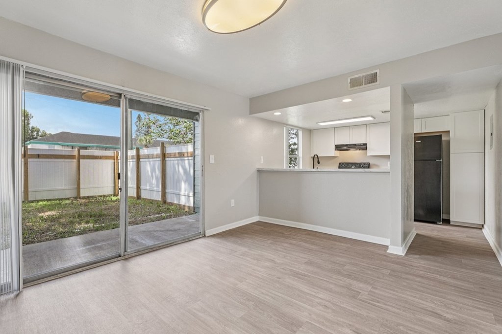 A spacious room with a sliding glass door leading to a backyard.