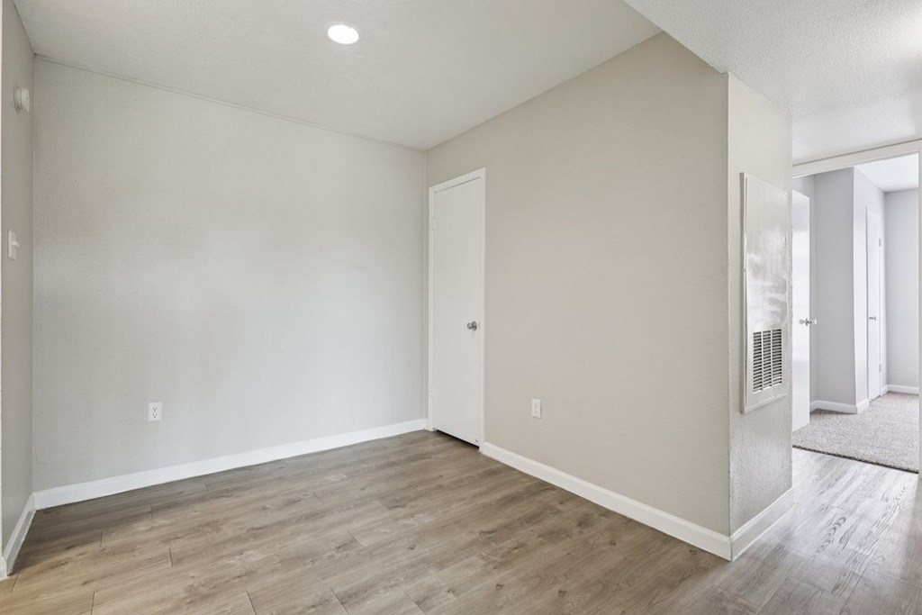 A room with a wooden floor and a door on the left side.