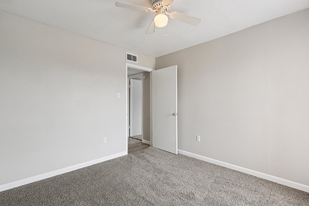 A room with a ceiling fan and carpeted floor.