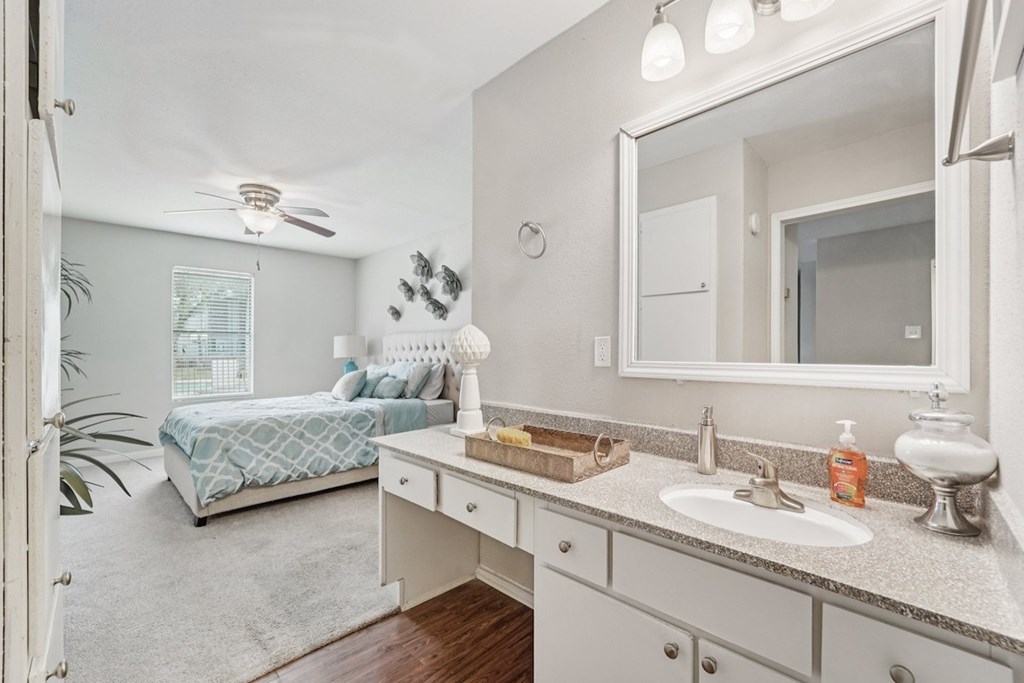 A bathroom with a bedroom area in the background.