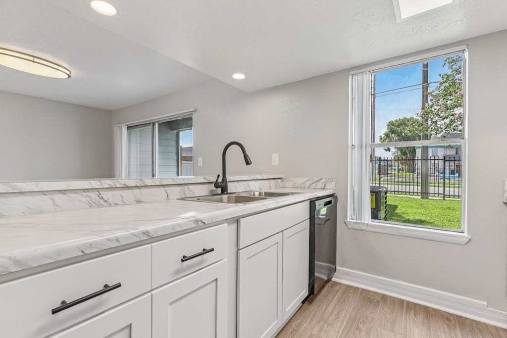 A kitchen with white cabinets and marble countertops.