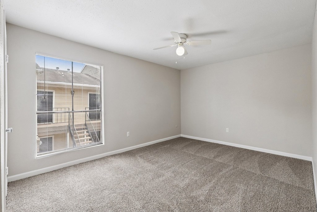 A room with a carpeted floor and a ceiling fan.