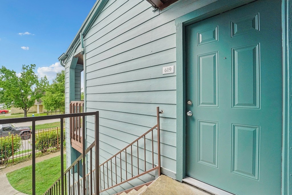 A blue door is on the right side of a house with a white siding.