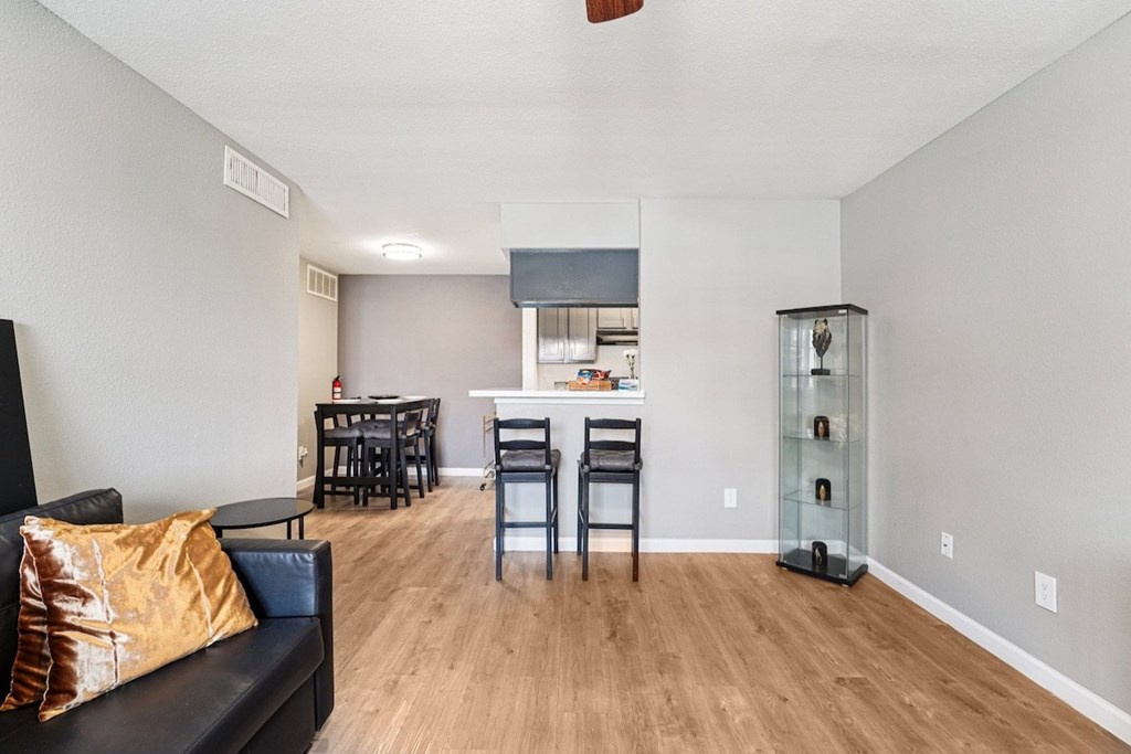 A living room with a black couch and a wooden floor.