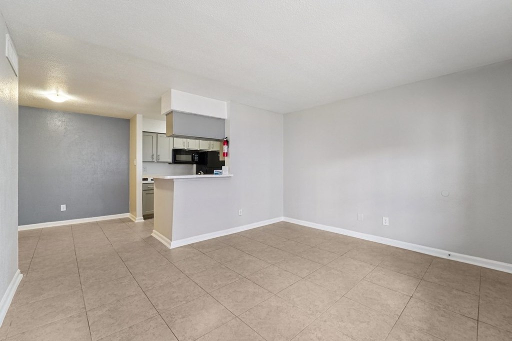 A spacious empty room with a kitchenette in the corner.