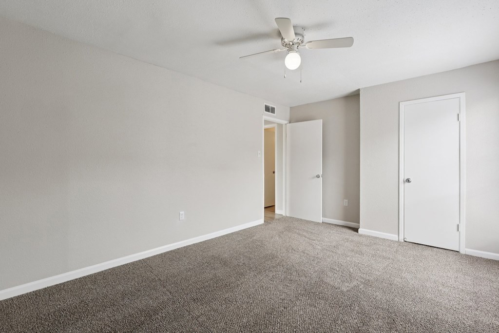 A room with a ceiling fan and carpeted floor.