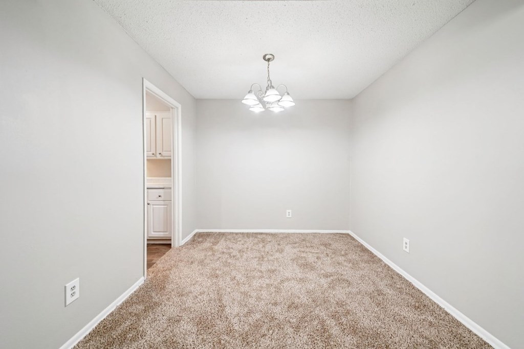 A room with a carpeted floor and a light hanging from the ceiling.at Hills at Hoover Apartments, Hoover, 35216