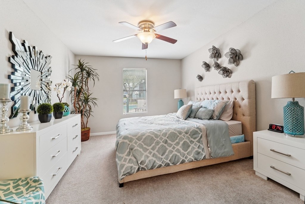 A bedroom with a bed, nightstands, and a ceiling fan.