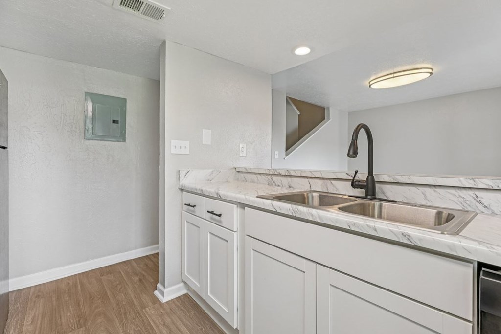 A white kitchen with a marble countertop and a modern sink.