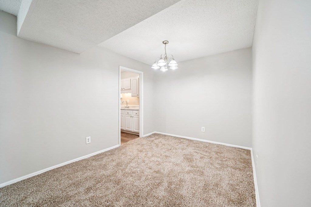 A carpeted room with a doorway leading to another room.at Hills at Hoover Apartments, Alabama