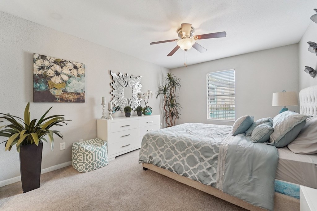 A bedroom with a bed, dresser, and potted plant.