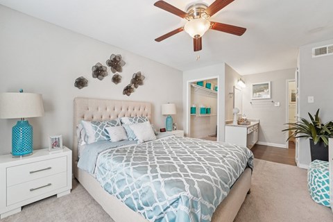 A bedroom with a large bed and a ceiling fan.